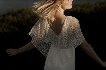 ICY Une robe de mariée bohème chic en dentelle de Calais et crêpe. Volant sur les épaules et quilles légères et transparentes sur les jambes.