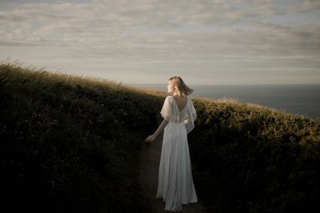 ICY Une robe de mariée bohème chic en dentelle de Calais et crêpe. Volant sur les épaules et quilles légères et transparentes sur les jambes.