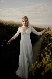 IPHIGENIE Une robe de mariée bohème chic en dentelle de Calais. Manches ¾ et grand V dos, avec ou sans ruban. Jupe vaporeuse en crêpe georgette de soie et plissé.