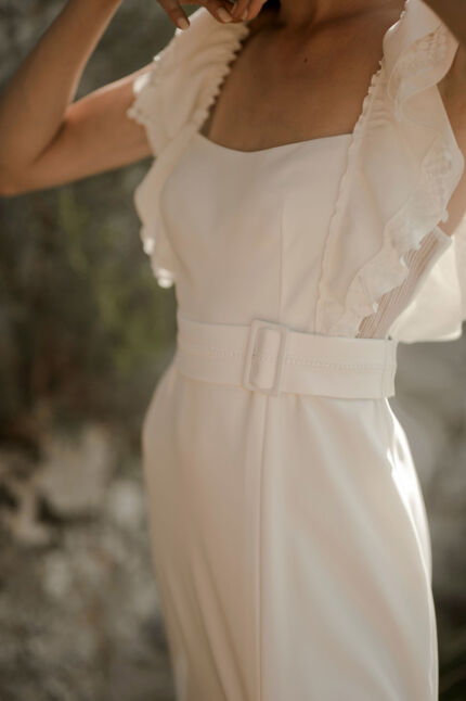 LA ROBE LYRICAL est une robe de mariée moderne en crêpe fluide et guipure écoresponsable. La jupe est fourreau, fendue sur la jambe, la taille marquée par une ceinture et son décolleté carré est orné de grands volants pour une mariée audacieuse. Robe de mariée LYRICAL