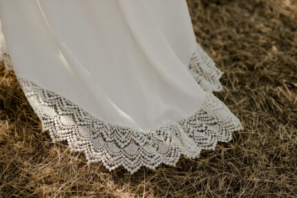 LA ROBE LYRICAL est une robe de mariée moderne en crêpe fluide et guipure écoresponsable. La jupe est fourreau, fendue sur la jambe, la taille marquée par une ceinture et son décolleté carré est orné de grands volants pour une mariée audacieuse. Robe de mariée LYRICAL