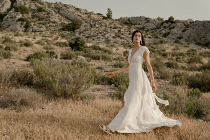 LA ROBE AIGUE MARINE est une robe de mariée moderne et minimaliste en crêpe de soie ultra fluide et légère agrémentée de petites manches volantes et d’une ceinture drapée en mousseline de soie. Elle est sensuelle et légère pour une mariée authentique. LA ROBE AIGUE MARINE