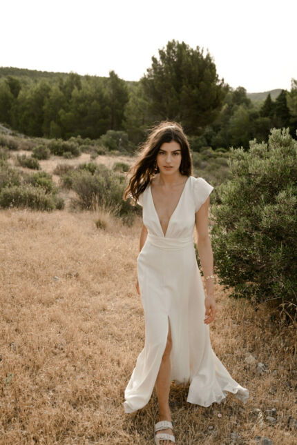 LA ROBE AIGUE MARINE est une robe de mariée moderne et minimaliste en crêpe de soie ultra fluide et légère agrémentée de petites manches volantes et d’une ceinture drapée en mousseline de soie. Elle est sensuelle et légère pour une mariée authentique. LA ROBE AIGUE MARINE