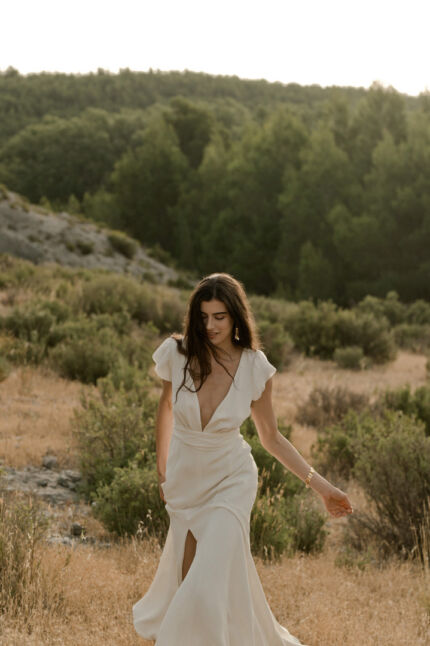 LA ROBE AIGUE MARINE est une robe de mariée moderne et minimaliste en crêpe de soie ultra fluide et légère agrémentée de petites manches volantes et d’une ceinture drapée en mousseline de soie. Elle est sensuelle et légère pour une mariée authentique. LA ROBE AIGUE MARINE