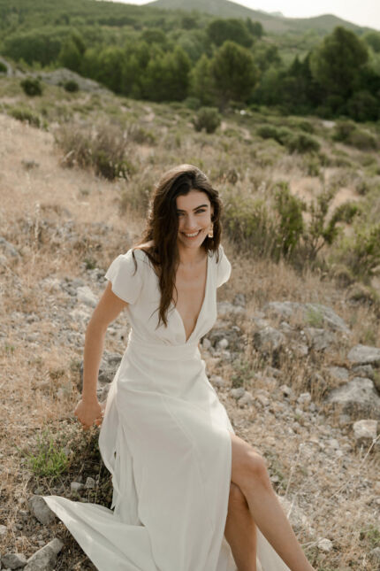 LA ROBE AIGUE MARINE est une robe de mariée moderne et minimaliste en crêpe de soie ultra fluide et légère agrémentée de petites manches volantes et d’une ceinture drapée en mousseline de soie. Elle est sensuelle et légère pour une mariée authentique. LA ROBE AIGUE MARINE