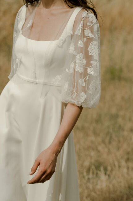 LA ROBE LONG LIVED est une robe de mariée moderne et minimaliste toute en crêpe écoresponsable ; une grande simplicité pour une mariée avec une forte personnalité. La blouse KISS en broderie coquelicots, made in France, lui apportera une touche espiègle et poétique pour une mariée bohème chic. LA ROBE LONG LIVED