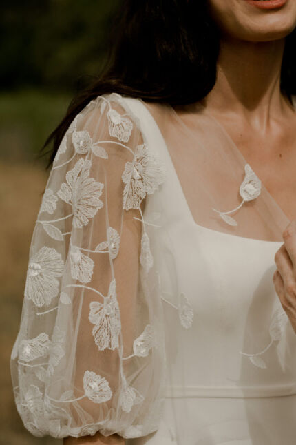 LA ROBE LONG LIVED est une robe de mariée moderne et minimaliste toute en crêpe écoresponsable ; une grande simplicité pour une mariée avec une forte personnalité. La blouse KISS en broderie coquelicots, made in France, lui apportera une touche espiègle et poétique pour une mariée bohème chic. LA ROBE LONG LIVED