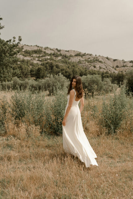 LA ROBE LONG LIVED est une robe de mariée moderne et minimaliste toute en crêpe écoresponsable ; une grande simplicité pour une mariée avec une forte personnalité. La blouse KISS en broderie coquelicots, made in France, lui apportera une touche espiègle et poétique pour une mariée bohème chic. LA ROBE LONG LIVED