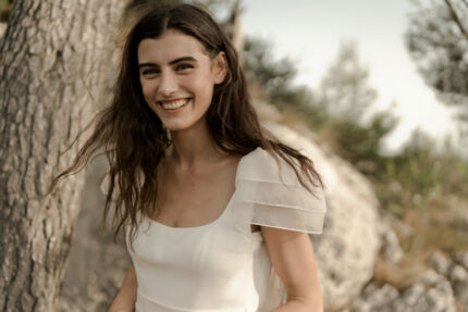 LA ROBE AQUA AURA est une robe de mariée moderne et couture en crêpe de soie. Sa silhouette est longiligne, son buste décolleté carré est habillé de manches courtes gonflantes et sa taille soulignée d’une ceinture finit sur une traine légère en organza, pour une mariée poétique. LA ROBE AQUA AURA