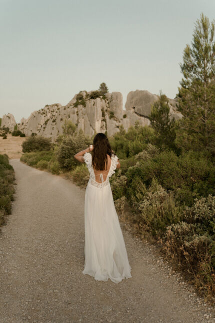 LA ROBE LUCKY LOVE est une robe de mariée en crêpe écoresponsable et mousseline de soie avec un buste tout en guipure et les épaules habillées de volants, pour une mariée débordante d’énergie et de gaîté de vivre. LA ROBE LUCKY LOVE