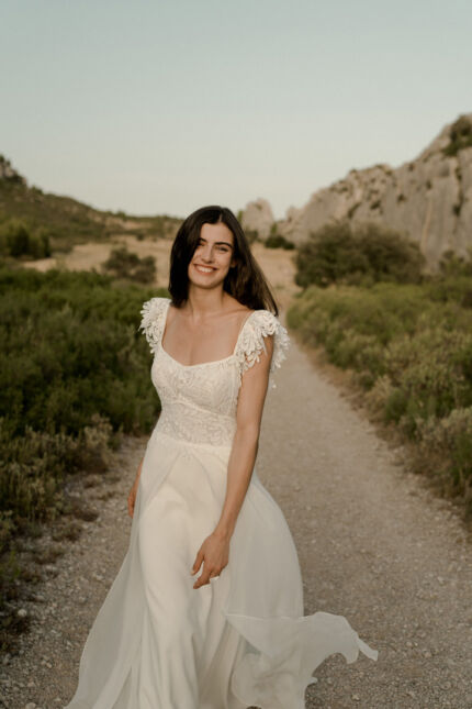 LA ROBE LUCKY LOVE est une robe de mariée en crêpe écoresponsable et mousseline de soie avec un buste tout en guipure et les épaules habillées de volants, pour une mariée débordante d’énergie et de gaîté de vivre. LA ROBE LUCKY LOVE