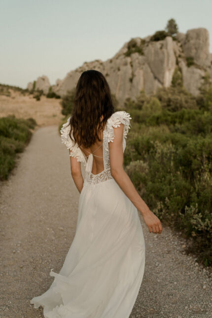 LA ROBE LUCKY LOVE est une robe de mariée en crêpe écoresponsable et mousseline de soie avec un buste tout en guipure et les épaules habillées de volants, pour une mariée débordante d’énergie et de gaîté de vivre. LA ROBE LUCKY LOVE