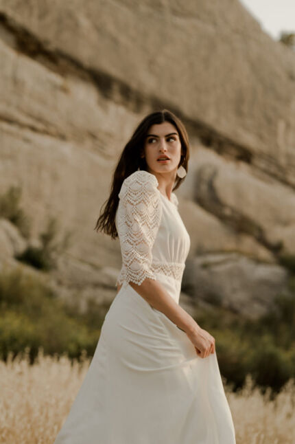 LA ROBE LOOKER est une robe de mariée moderne très chic. En crêpe fluide et guipure écoresponsable, ses manches rehaussées, sa taille transparente et son grand décolleté dans le dos apportent force et originalité pour une mariée affirmée. Bijoux LA ROBE LOOKER