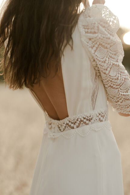LA ROBE LOOKER est une robe de mariée moderne très chic. En crêpe fluide et guipure écoresponsable, ses manches rehaussées, sa taille transparente et son grand décolleté dans le dos apportent force et originalité pour une mariée affirmée. Bijoux LA ROBE LOOKER