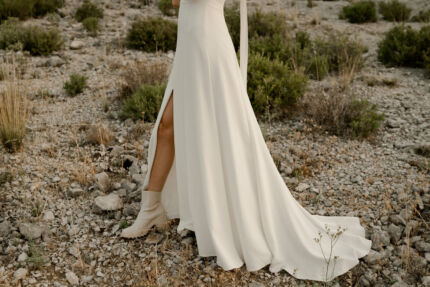 LA ROBE AMBRE est une robe de mariée moderne chic et couture toute en crêpe de soie. Des manches gonflantes à plis dessinent les épaules, son grand décolleté sensuel et sa fente conviendront à une mariée amazone des temps modernes. LA ROBE AMBRE