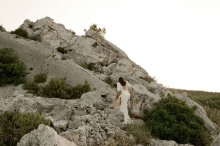 LA ROBE AMBRE est une robe de mariée moderne chic et couture toute en crêpe de soie. Des manches gonflantes à plis dessinent les épaules, son grand décolleté sensuel et sa fente conviendront à une mariée amazone des temps modernes. LA ROBE AMBRE