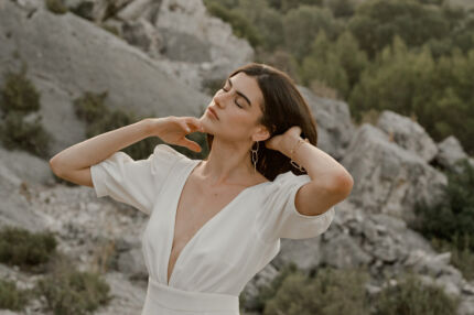 LA ROBE AMBRE est une robe de mariée moderne chic et couture toute en crêpe de soie. Des manches gonflantes à plis dessinent les épaules, son grand décolleté sensuel et sa fente conviendront à une mariée amazone des temps modernes. LA ROBE AMBRE