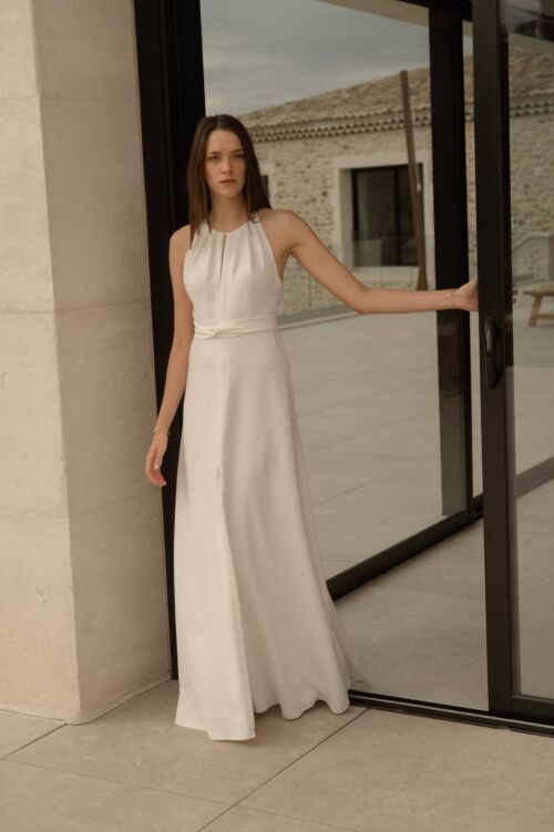 NAÏS est une robe de mariée moderne. On aimera son buste plissé et son dos audacieux en broderie de grandes fleurs.