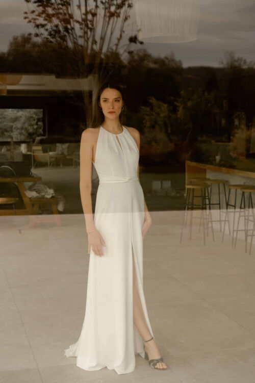 NAÏS est une robe de mariée moderne. On aimera son buste plissé et son dos audacieux en broderie de grandes fleurs.