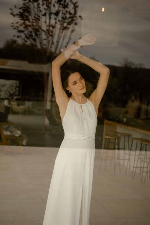 NAÏS est une robe de mariée moderne. On aimera son buste plissé et son dos audacieux en broderie de grandes fleurs.