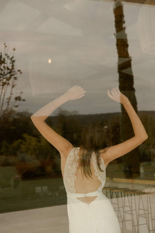 NAÏS est une robe de mariée moderne. On aimera son buste plissé et son dos audacieux en broderie de grandes fleurs.