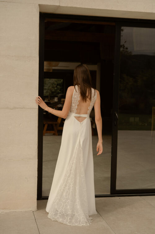 NAÏS est une robe de mariée moderne. On aimera son buste plissé et son dos audacieux en broderie de grandes fleurs.