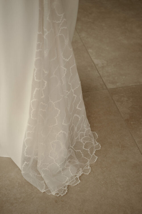 NAÏS est une robe de mariée moderne. On aimera son buste plissé et son dos audacieux en broderie de grandes fleurs.