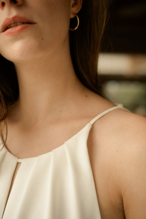 NAÏS est une robe de mariée moderne. On aimera son buste plissé et son dos audacieux en broderie de grandes fleurs.