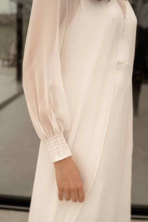 OH MY GOD est une longue sur-robe de mariée ou un manteau de mariée, toute en mousseline de soie. Les poignets et le col sont faits de smocks pour un mariage avec une note couture.