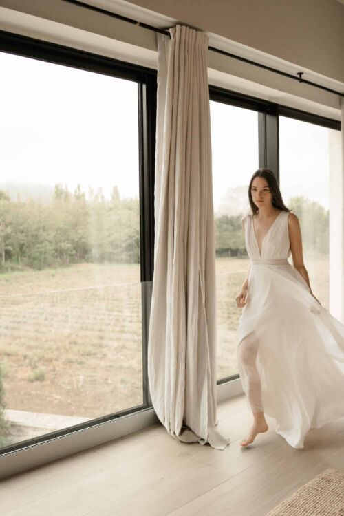 NOBILITA est une robe de mariée moderne, toute en mousseline de soie, plissée sur le buste. C'est une robe de mariée sans manches qui étonnera par sa très grande légèreté.