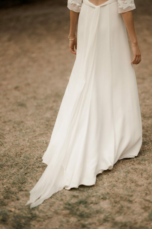 OLYMPE est une robe de mariée en crêpe de soie qui séduira par le style vintage que donne cette magnifique mousseline brodée de feuilles sur les manches et le dos.