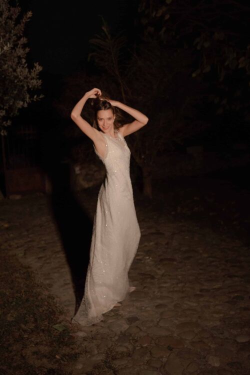 OPERA est une sur-robe de mariée entièrement perlée pour un mariage glamour, portée sur une robe en soie à fines bretelles .