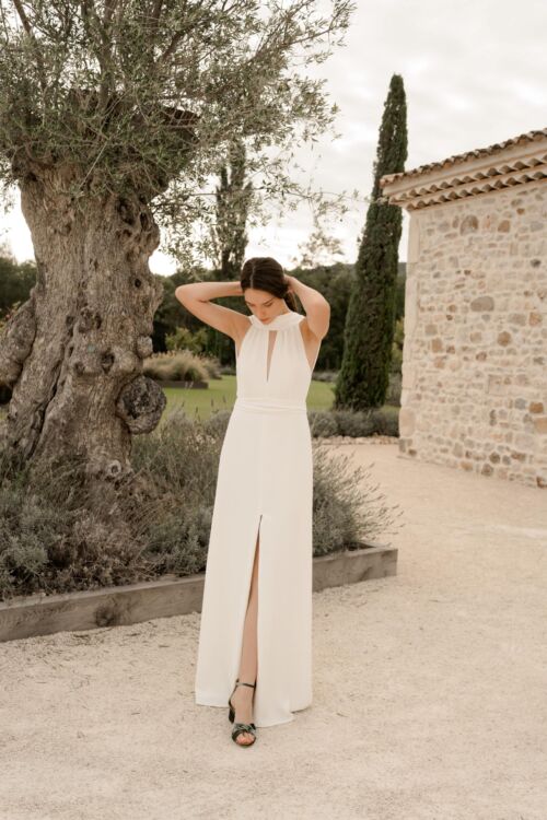 NUNCIA est une robe de mariée moderne et chic. L'élégance du col charmera celles qui ne veulent pas de décolleté.