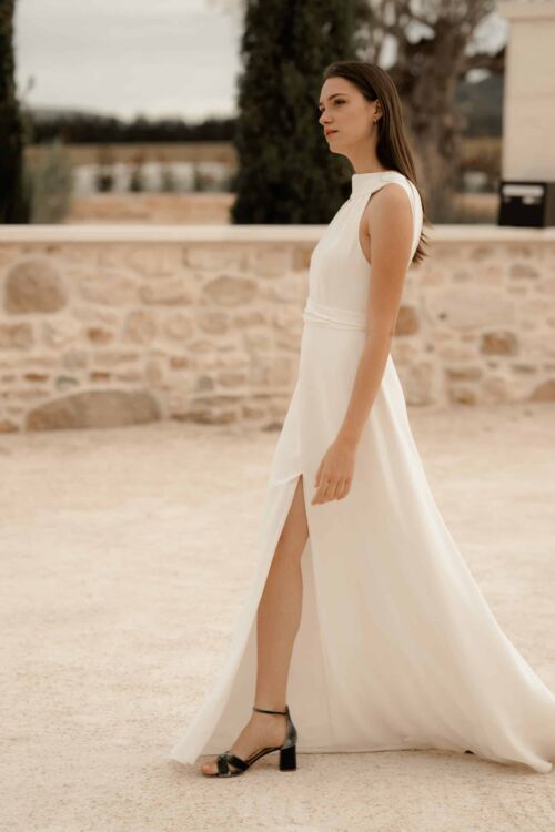 NUNCIA est une robe de mariée moderne et chic. L'élégance du col charmera celles qui ne veulent pas de décolleté.