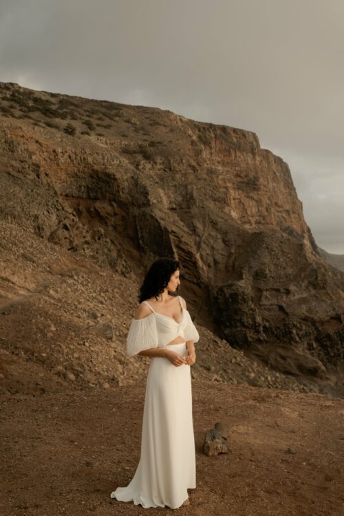 PODER PARA TI est un ensemble de mariée moderne et sexy, composé d'un bustier de mariée drapé de mousseline de soie plissée et d'une jupe de mariée fluide en crêpe de soie. Les manches bouffantes de cet ensemble de mariage sont amovibles.