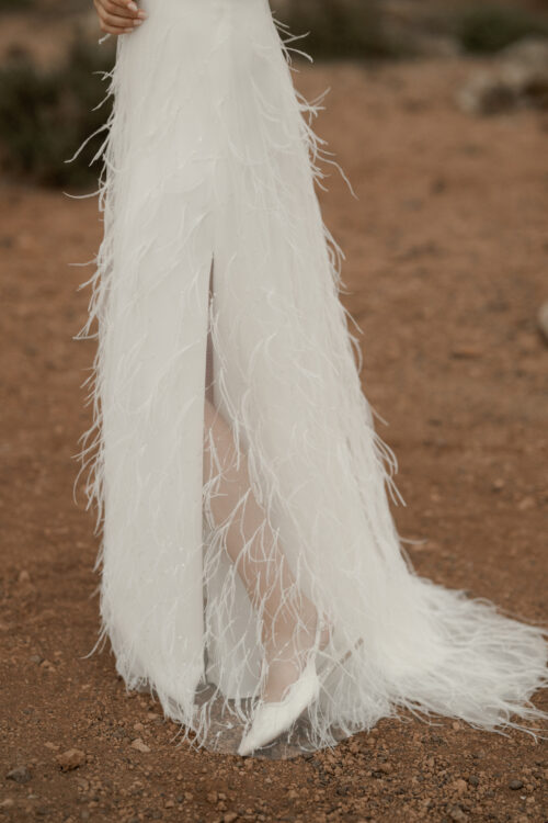 ORIGINAL est un ensemble de mariée audacieux pour une tenue de mariée moderne. Il est composé d'un bustier de mariage asymétrique drapé de crêpe de soie et d'une jupe de mariée en broderie de plumes. La jupe de mariée, fendue sur le côté, en fait une tenue de mariée sexy. L'audace de cette tenue de mariée sera parfaite pour un mariage chic et rock.