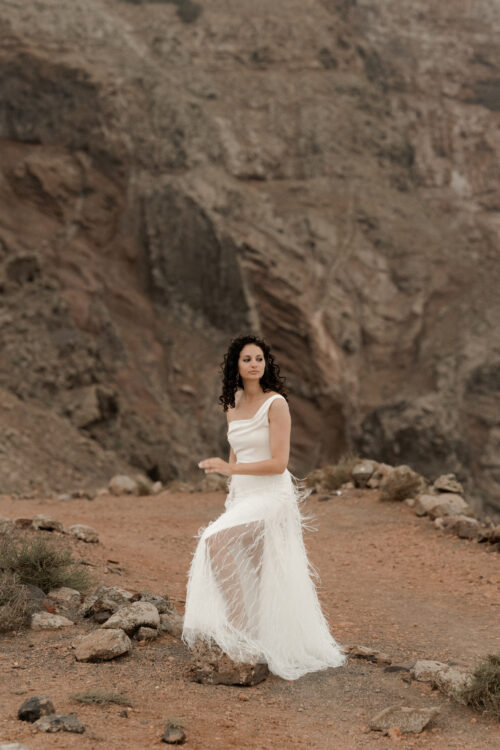 ORIGINAL est un ensemble de mariée audacieux pour une tenue de mariée moderne. Il est composé d'un bustier de mariage asymétrique drapé de crêpe de soie et d'une jupe de mariée en broderie de plumes. La jupe de mariée, fendue sur le côté, en fait une tenue de mariée sexy. L'audace de cette tenue de mariée sera parfaite pour un mariage chic et rock.