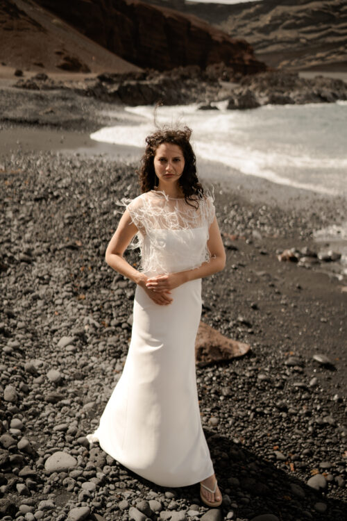 Passion est une robe de mariée minimaliste en crêpe eco-friendly avec de fines bretelles et une fente sur le côté. Son dos-nu original en fait une robe de mariée moderne. Cette robe de mariée simple pourra être portée avec PROSPER notre petit top de mariage transparent en broderie de perles ou en broderie de plumes. Bijoux @anthemis.paris