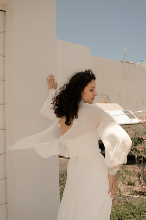 PURITY est une robe de mariée bustier en crêpe eco-friendly avec la taille soulignée d’une ceinture drapée. C’est une robe de mariée minimaliste pour un mariage chic. PABLO est une blouse de mariée en mousseline de soie avec les poignets et le col en fine broderie qui apportera une note très chic à cette tenue de mariée simple.