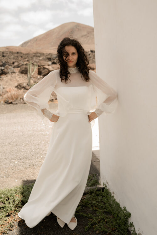 PURITY est une robe de mariée bustier en crêpe eco-friendly avec la taille soulignée d’une ceinture drapée. C’est une robe de mariée minimaliste pour un mariage chic. PABLO est une blouse de mariée en mousseline de soie avec les poignets et le col en fine broderie qui apportera une note très chic à cette tenue de mariée simple.
