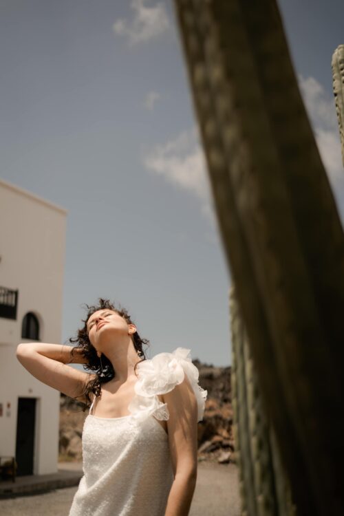 PEARLS est une robe de mariée courte en crêpe et broderie de perles, ornée de grosses fleurs sur l’épaule. Elle sera parfaite comme tenue de mariée civile ou pour un mariage simple. Bijoux @anthemis.paris