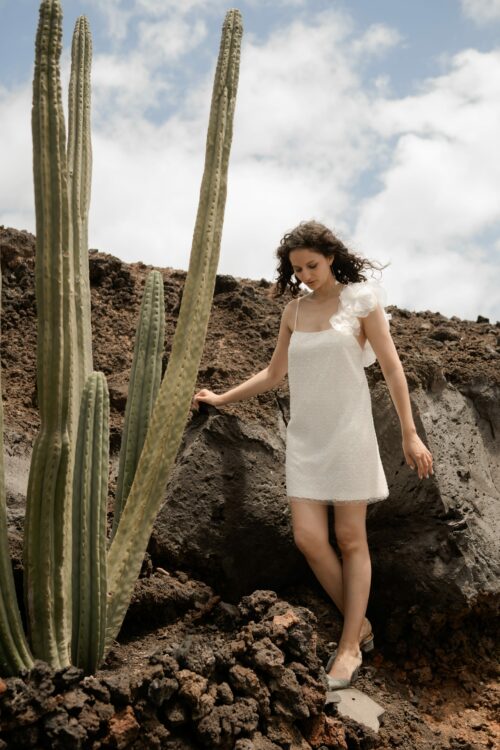 PEARLS est une robe de mariée courte en crêpe et broderie de perles, ornée de grosses fleurs sur l’épaule. Elle sera parfaite comme tenue de mariée civile ou pour un mariage simple. Bijoux @anthemis.paris Chaussures @flordeasoka_paris