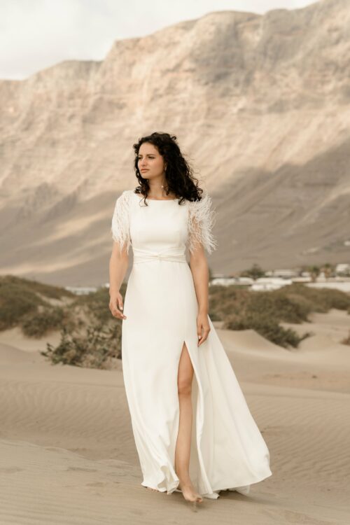 PROMISE est une robe de mariée moderne en crêpe eco-friendly avec des manches courtes en broderie de plumes. C’est une robe de mariée chic avec une jupe de mariée ample et fendue. Cette robe de mariée dos nu sera parfaite pour un mariage cool et chic. En réalisant votre robe de mariée sur mesure, vous pourrez opter pour les manches de votre choix. Bijoux @anthemis.paris