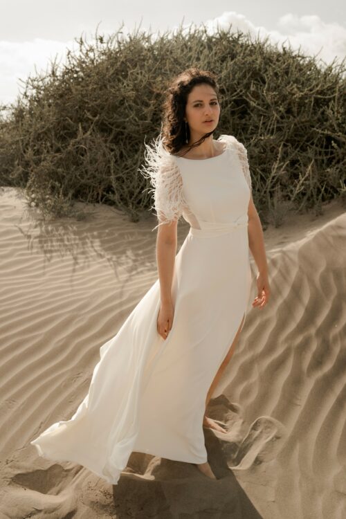 PROMISE est une robe de mariée moderne en crêpe eco-friendly avec des manches courtes en broderie de plumes. C’est une robe de mariée chic avec une jupe de mariée ample et fendue. Cette robe de mariée dos nu sera parfaite pour un mariage cool et chic. En réalisant votre robe de mariée sur mesure, vous pourrez opter pour les manches de votre choix. Bijoux @anthemis.paris