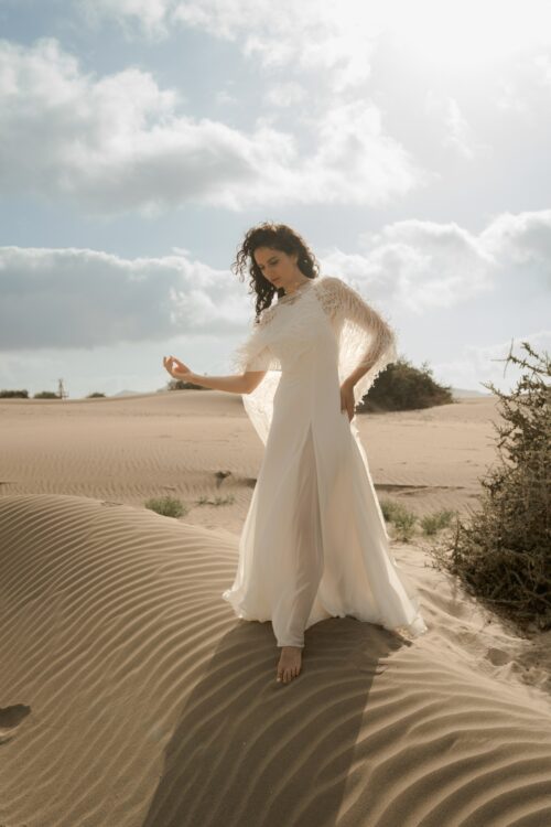 PARADISE est une robe de mariée chic en crêpe de soie. Son décolleté « emmanchures américaines » et son dos habillé de bretelles en font une robe de mariée minimaliste élégante. La jupe est incrustée de mousseline de soie pour faire une robe de mariée fluide. Bijoux @anthemis.paris .