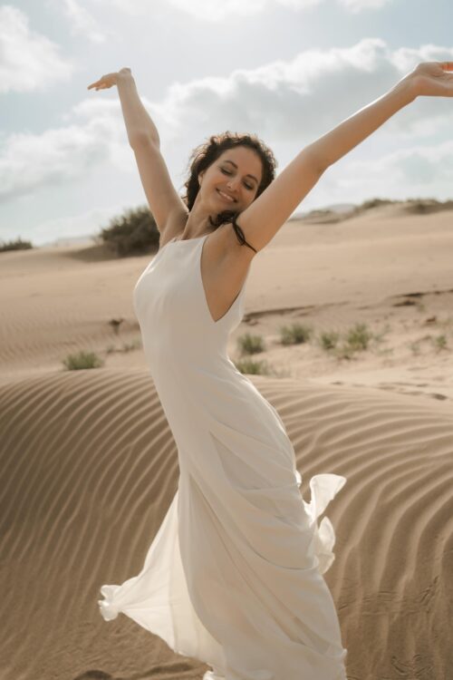 PARADISE est une robe de mariée chic en crêpe de soie. Son décolleté « emmanchures américaines » et son dos habillé de bretelles en font une robe de mariée minimaliste élégante. La jupe est incrustée de mousseline de soie pour faire une robe de mariée fluide. Bijoux @anthemis.paris .