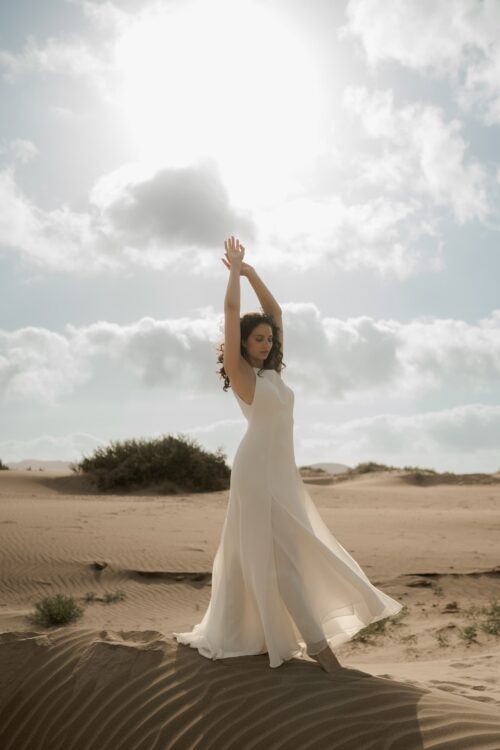 PARADISE est une robe de mariée chic en crêpe de soie. Son décolleté « emmanchures américaines » et son dos habillé de bretelles en font une robe de mariée minimaliste élégante. La jupe est incrustée de mousseline de soie pour faire une robe de mariée fluide. Bijoux @anthemis.paris