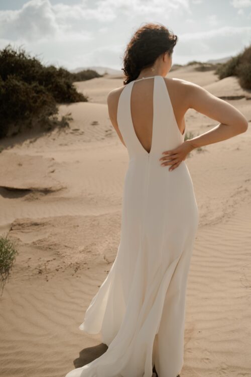 PARADISE est une robe de mariée chic en crêpe de soie. Son décolleté « emmanchures américaines » et son dos habillé de bretelles en font une robe de mariée minimaliste élégante. La jupe est incrustée de mousseline de soie pour faire une robe de mariée fluide. Bijoux @anthemis.paris .