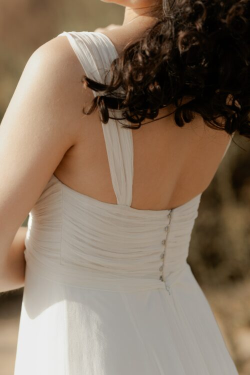 PRECIOSO est une robe de mariée empire toute en mousseline de soie. Son buste est drapé de mousseline de soie plissée. Sa jupe de mariée en mousseline de soie voluptueuse est fendue au milieu devant. C’est une robe de mariée légère pour un mariage romantique et moderne. Bijoux @anthemis.paris