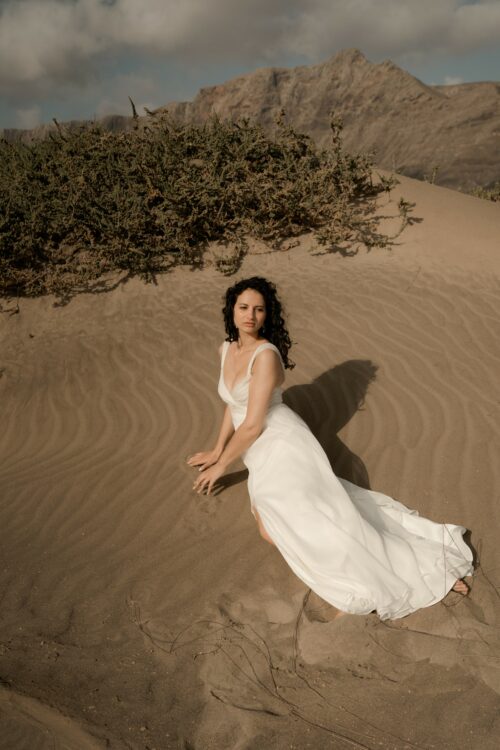 PRECIOSO est une robe de mariée empire toute en mousseline de soie. Son buste est drapé de mousseline de soie plissée. Sa jupe de mariée en mousseline de soie voluptueuse est fendue au milieu devant. C’est une robe de mariée légère pour un mariage romantique et moderne. Bijoux @anthemis.paris